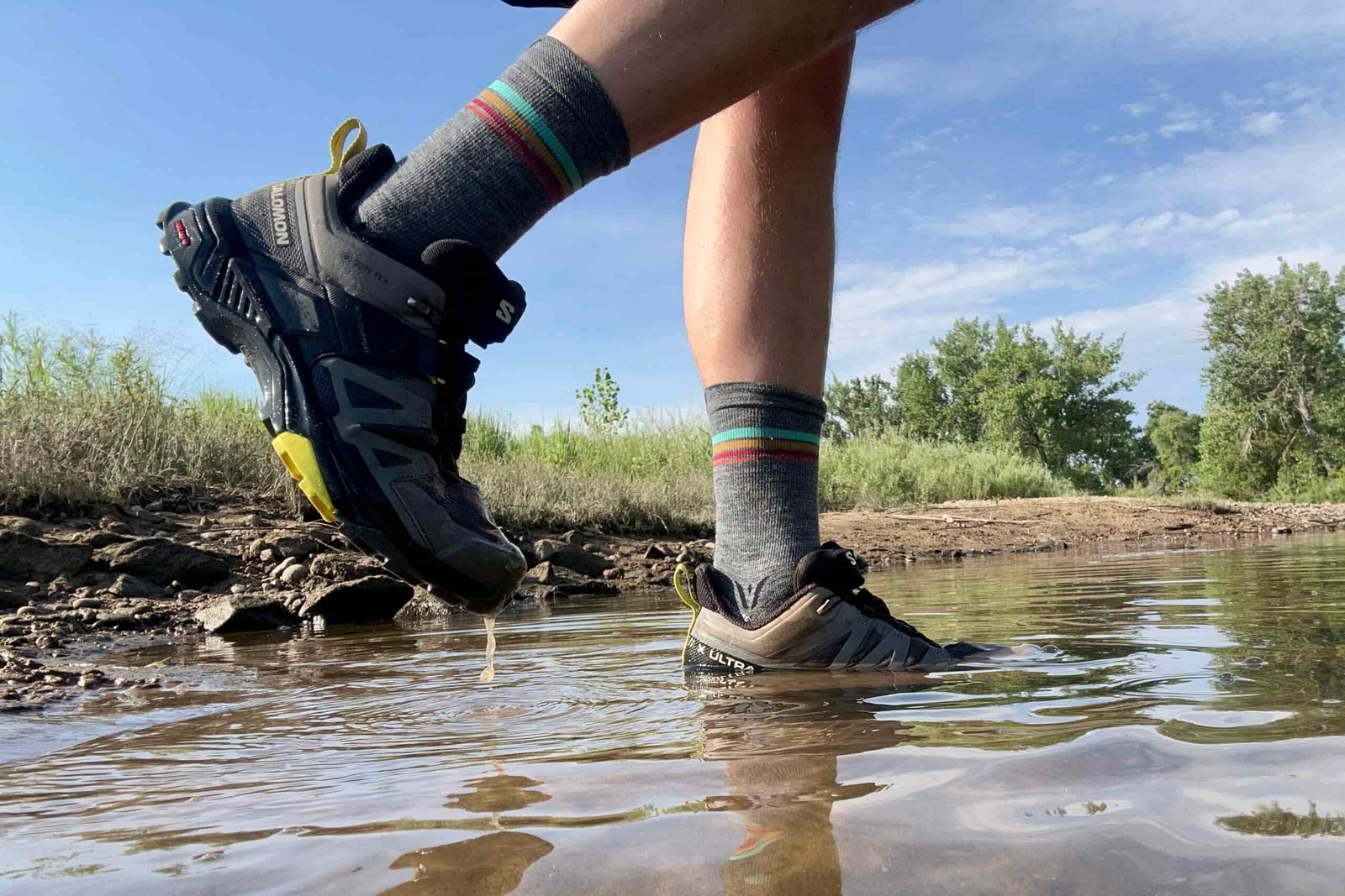 A close up shot of a man wearing the Salomon Ultra GTX 4 shoes in mud and water.