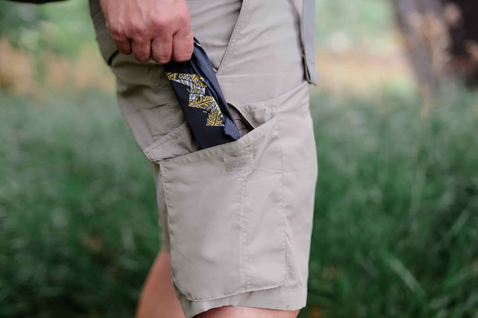 A hand grabbing sunglasses from the side pocket on a pair of shorts