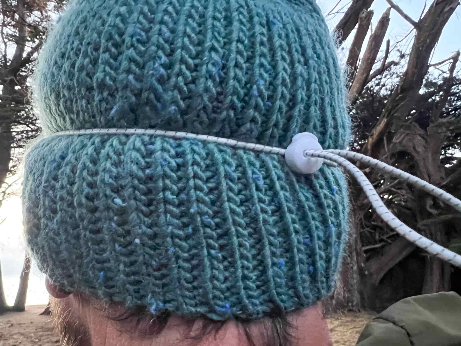 The image shows the back of a hikers head and a white shock cord headlamp strap