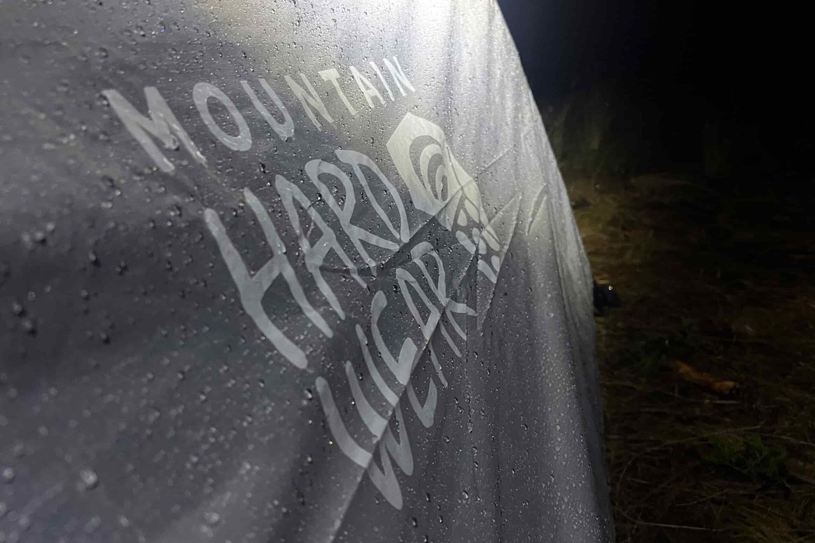 The image shows the wet rainfly of the Mountain Hardware Mineral King 3 illuminated by a headlamp at night. The background is dark.