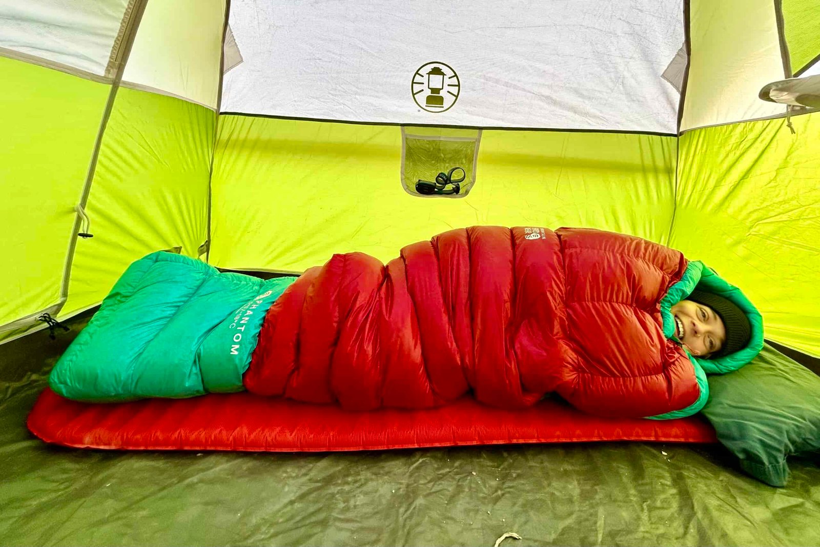 A woman smiles from her sleeping bag in a profile view.