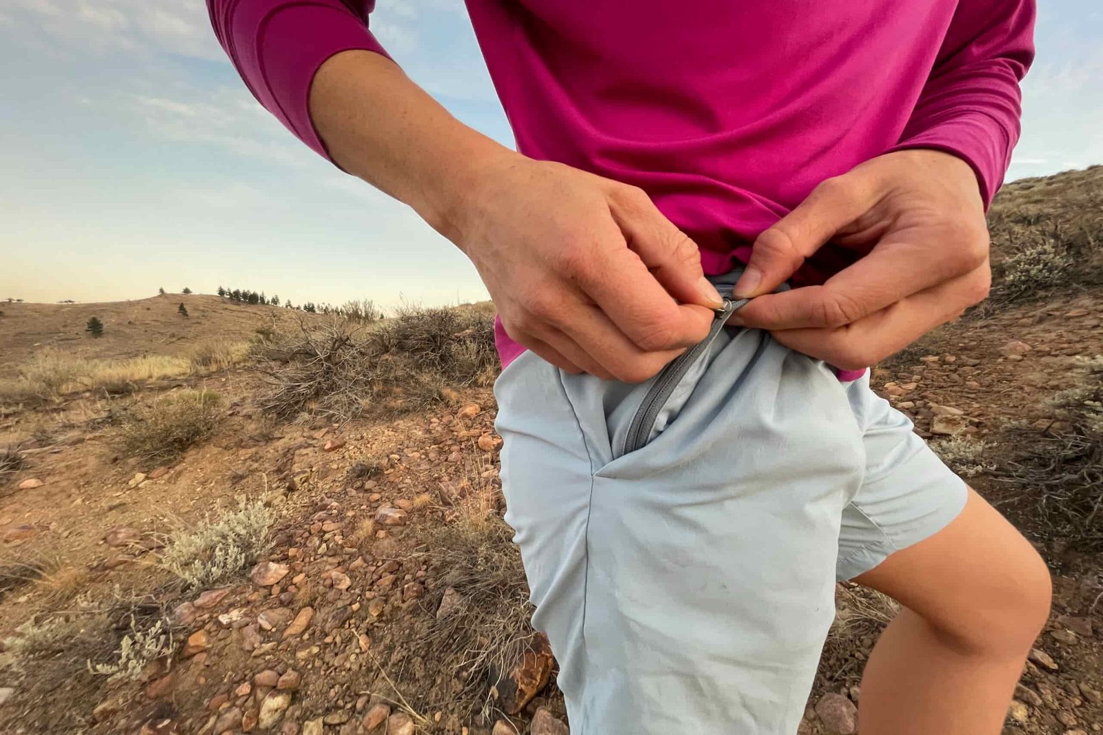 a hiker unzipping a hidden zipper pocket inside the deep waist pocket