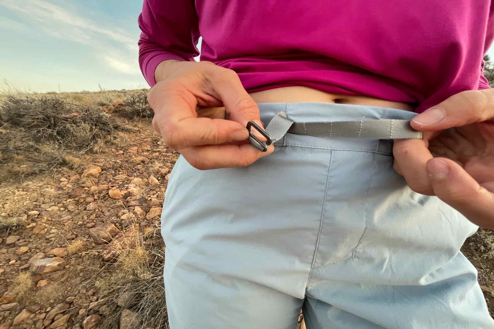 A hiker adjusting the built-in hook belt on the houdini wadi
