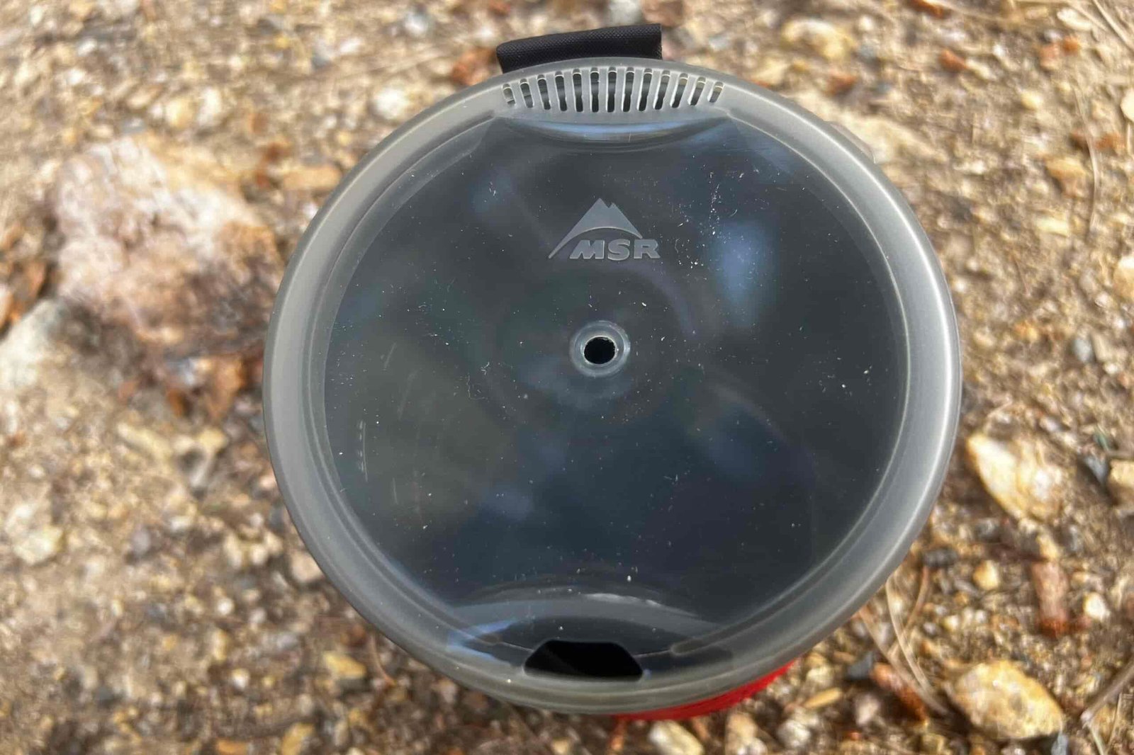 A top view of the lid of the MSR WindBurner on a gravel background.