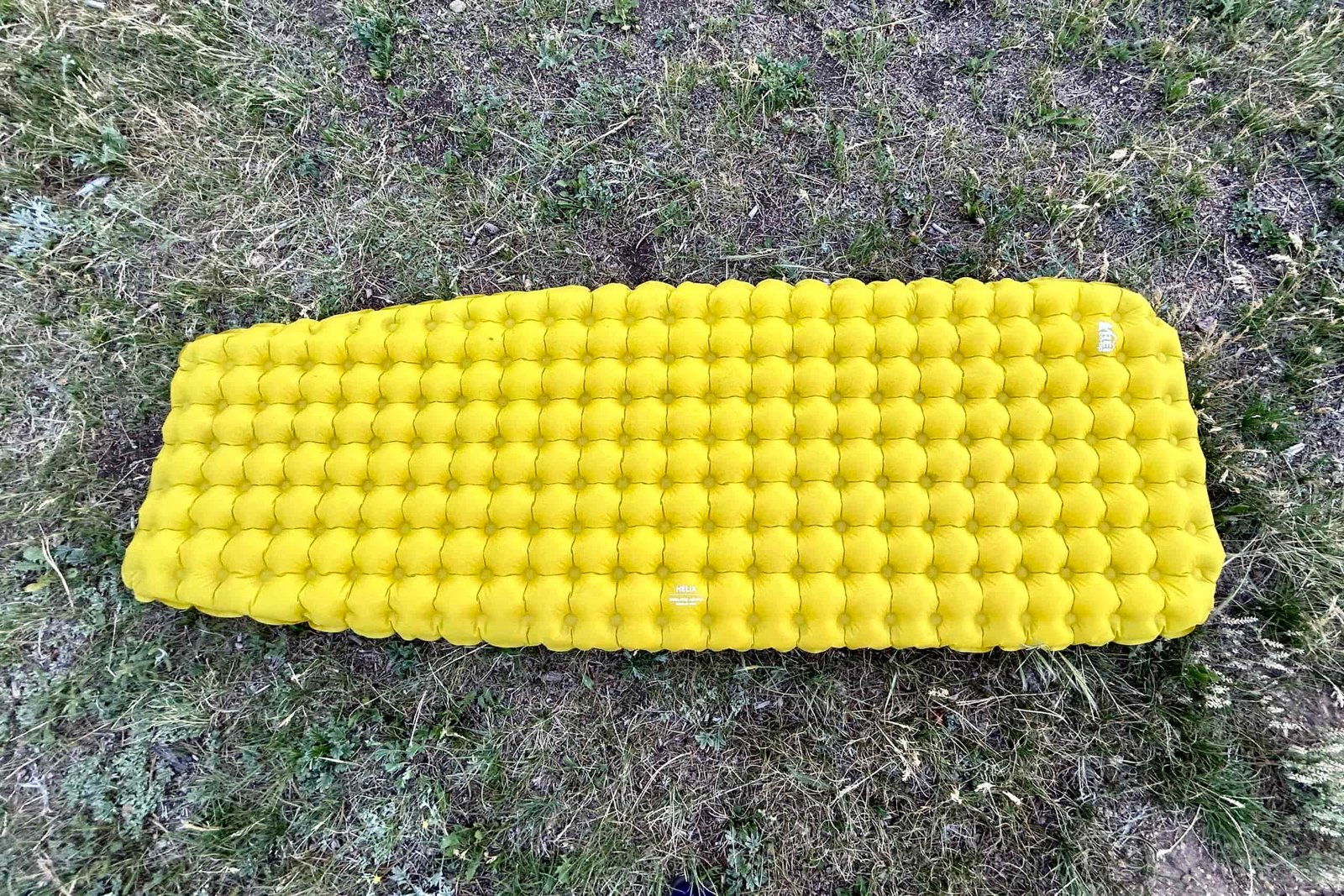 A yellow sleeping pad lies flat on the ground.
