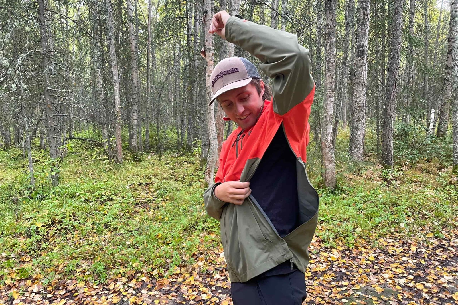 A man unzips the vents of his rain jacket.