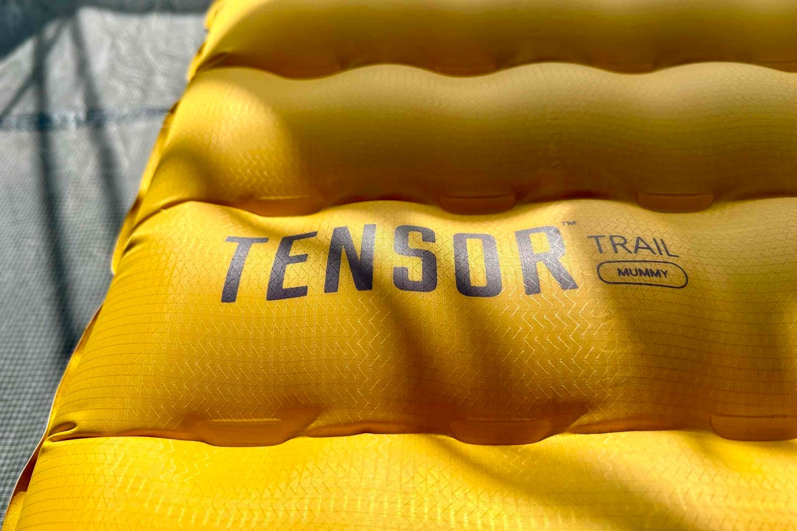 Close up of a Tensor Trail sleeping pad laid out on the ground with its baffles inflated.