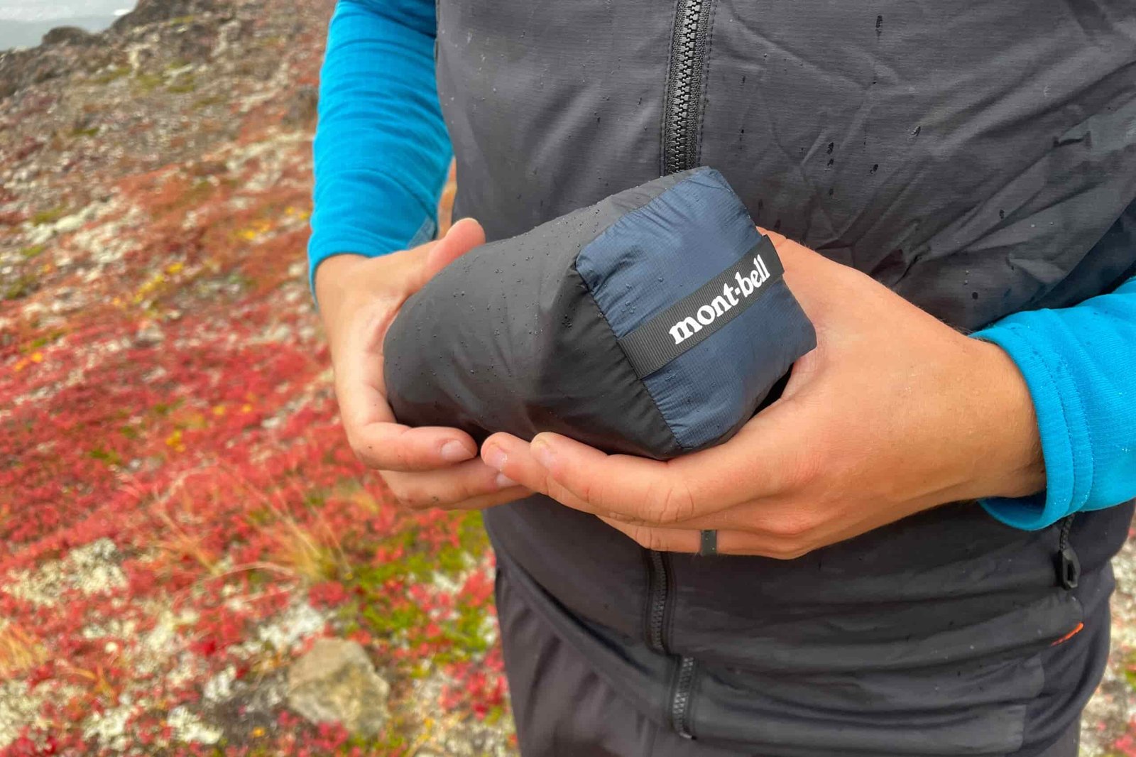 A man holds a rain jacket packed into a bundle.