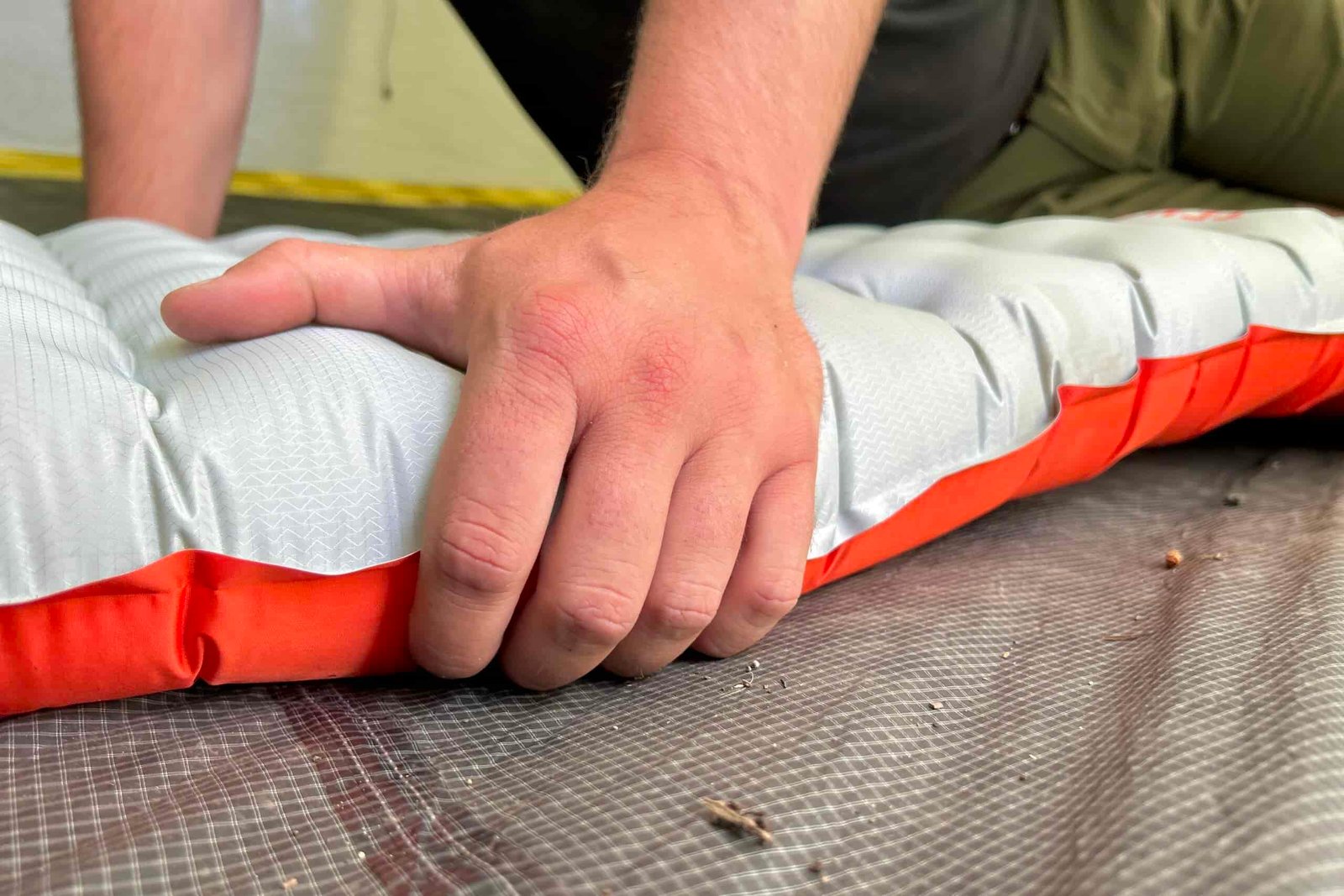 A person grips the side of a sleeping pad.