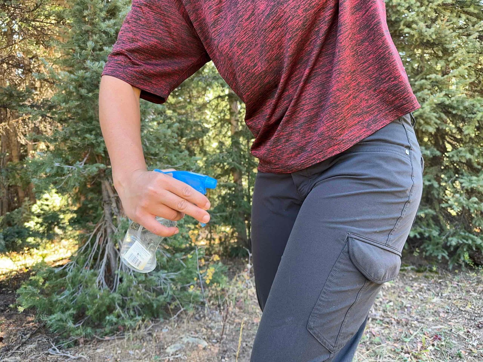 a gear analyst spraying water on their pants to test water resistance of the polyester on the kuhl freeflex pants