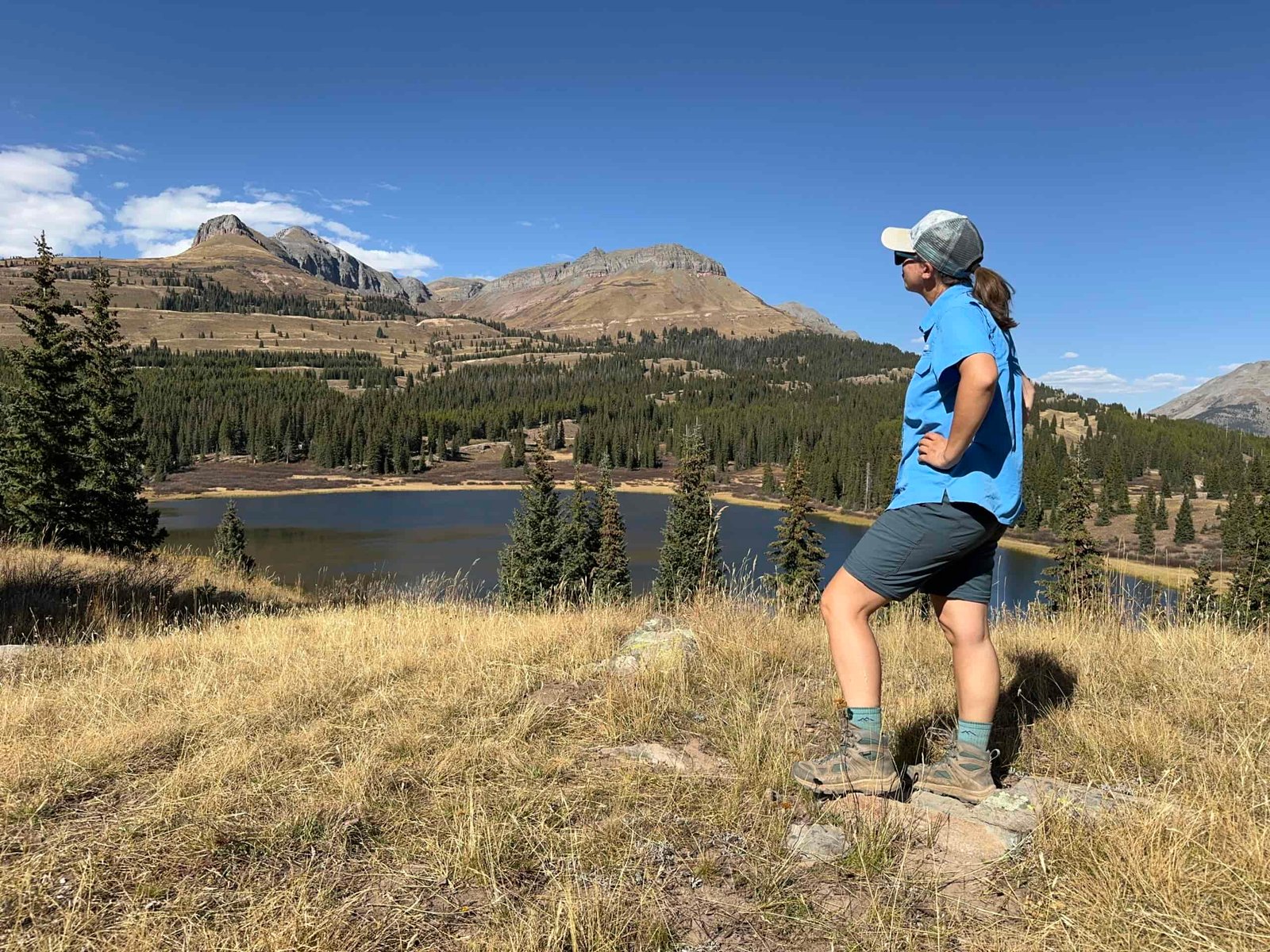 a backpacker wearing the REI convertible pants in shorts mode overlooking a lake