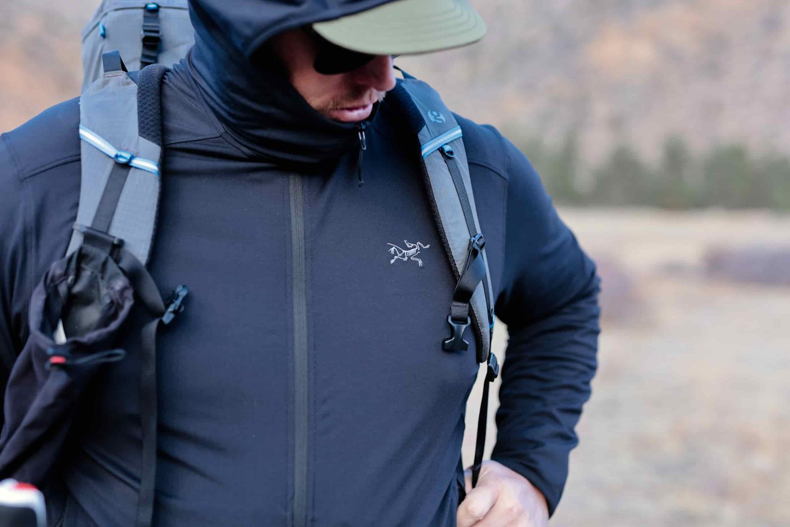 Man wears a backpack and looks down at the trail.