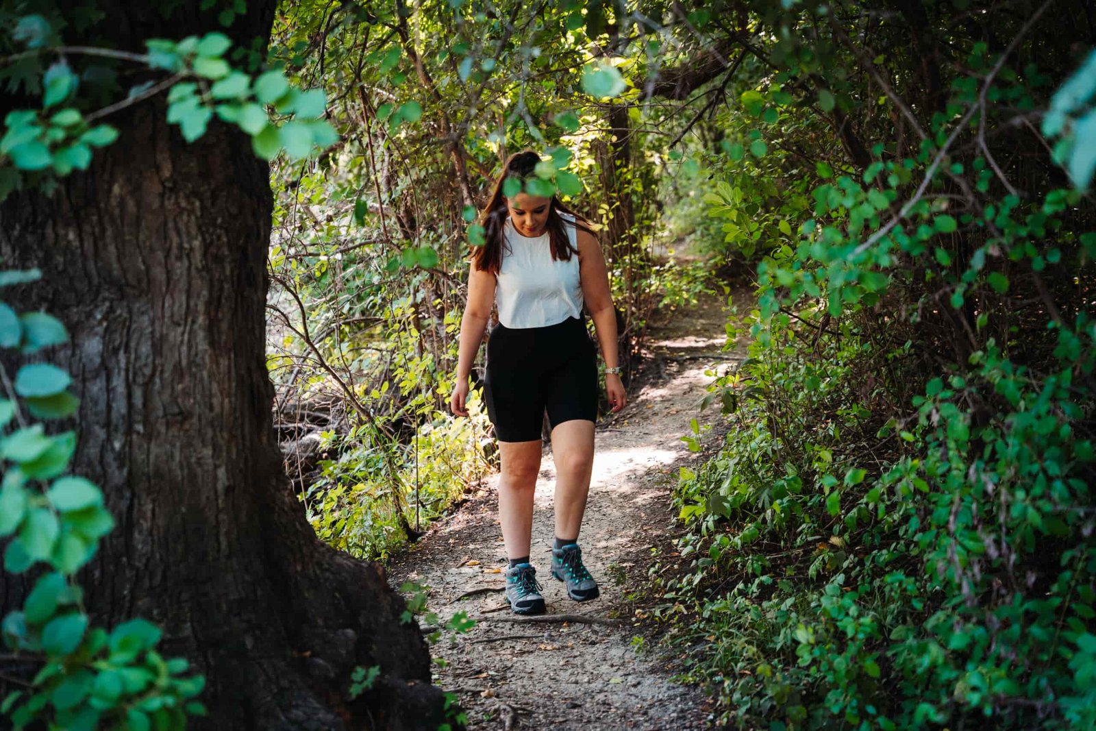 Hiker walking down a shaded trail wearing Merrell Moab 3 WP Women's Hiking Boots