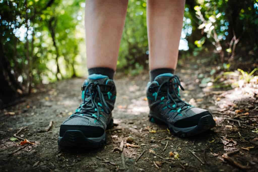 A hiker standing on a shaded trail wearing the Merrell Moab 3 WP Women's Hiking Boots
