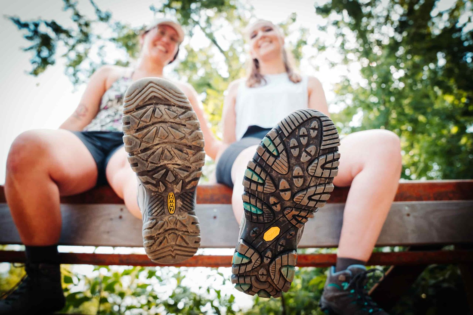 Two hikers sitting on a bridge wearing Keen Targhee IV WP and Merrell Moab 3 WP Women's Hiking Boots