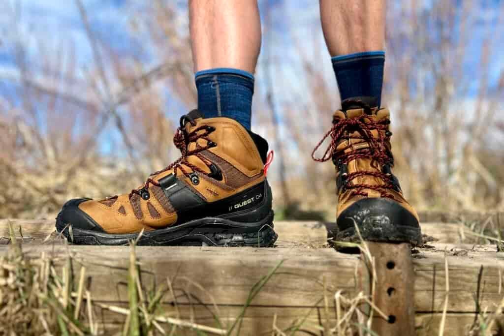Close-up image from the knees down of a person walking in hiking boots in a wilderness area.