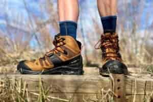 Close-up image from the knees down of a person walking in hiking boots in a wilderness area.