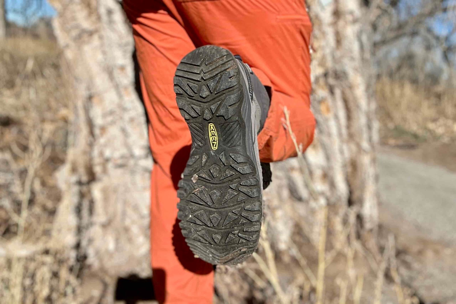 Close up image of a person showing the tread on the bottom of their boots.