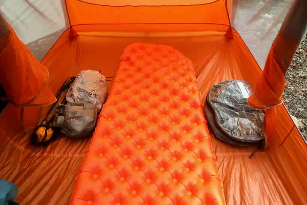 a sea to summit ultralight insulated sleeping pad inflated in a backpacking tent with an ultralight pack and pod beside it.