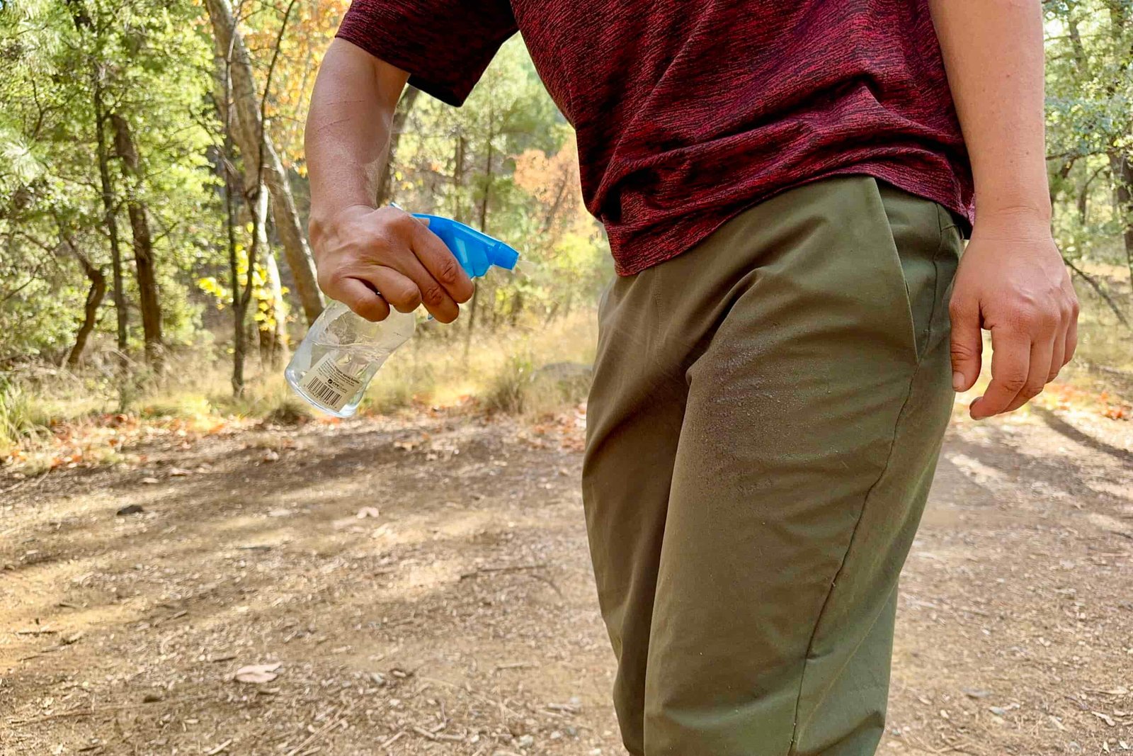 A hand is spraying the Patagonia Happy Hike pants with water from a squirt bottle.