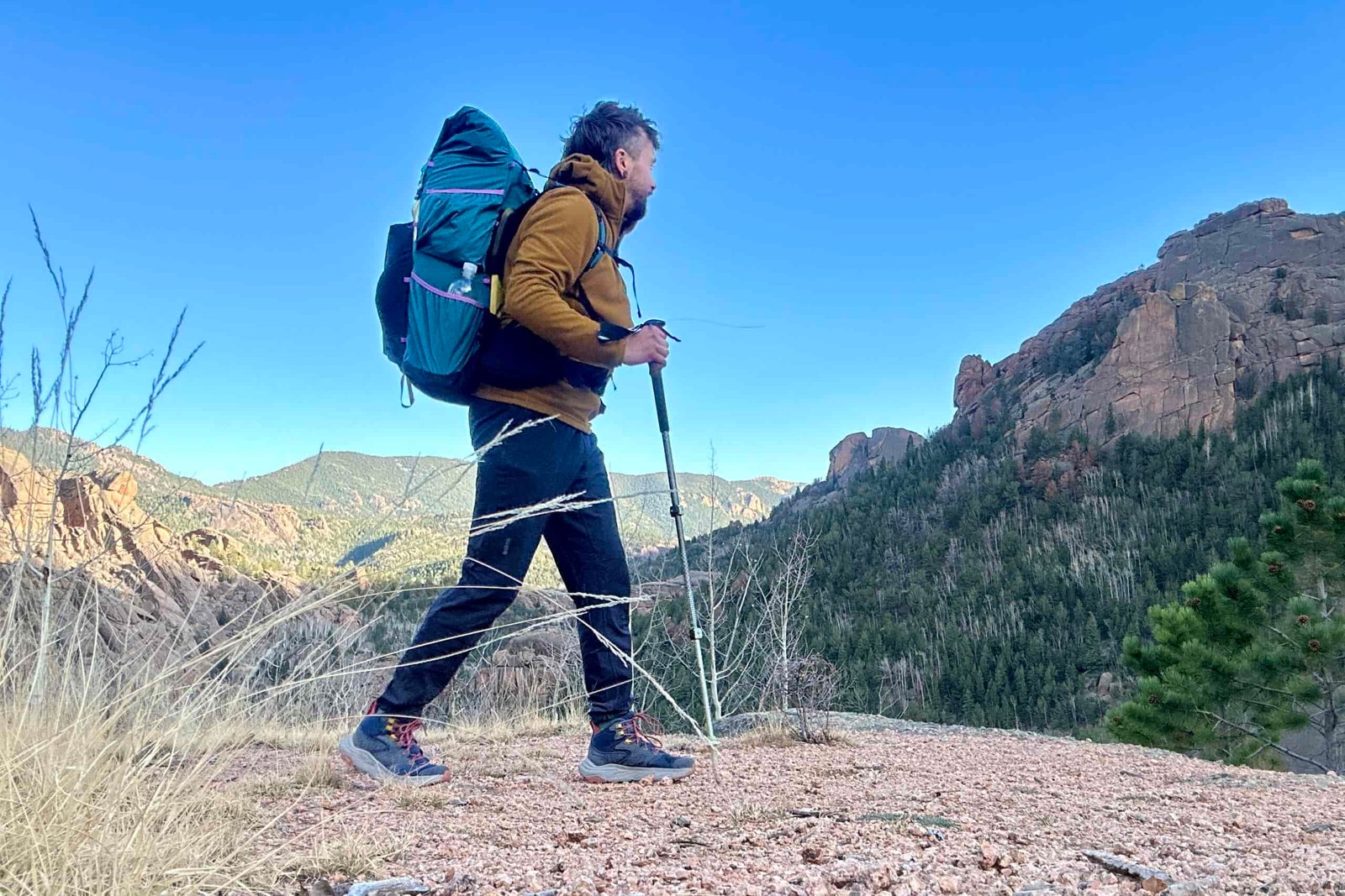 A man with a large backpacking backpack walks in a forest setting.