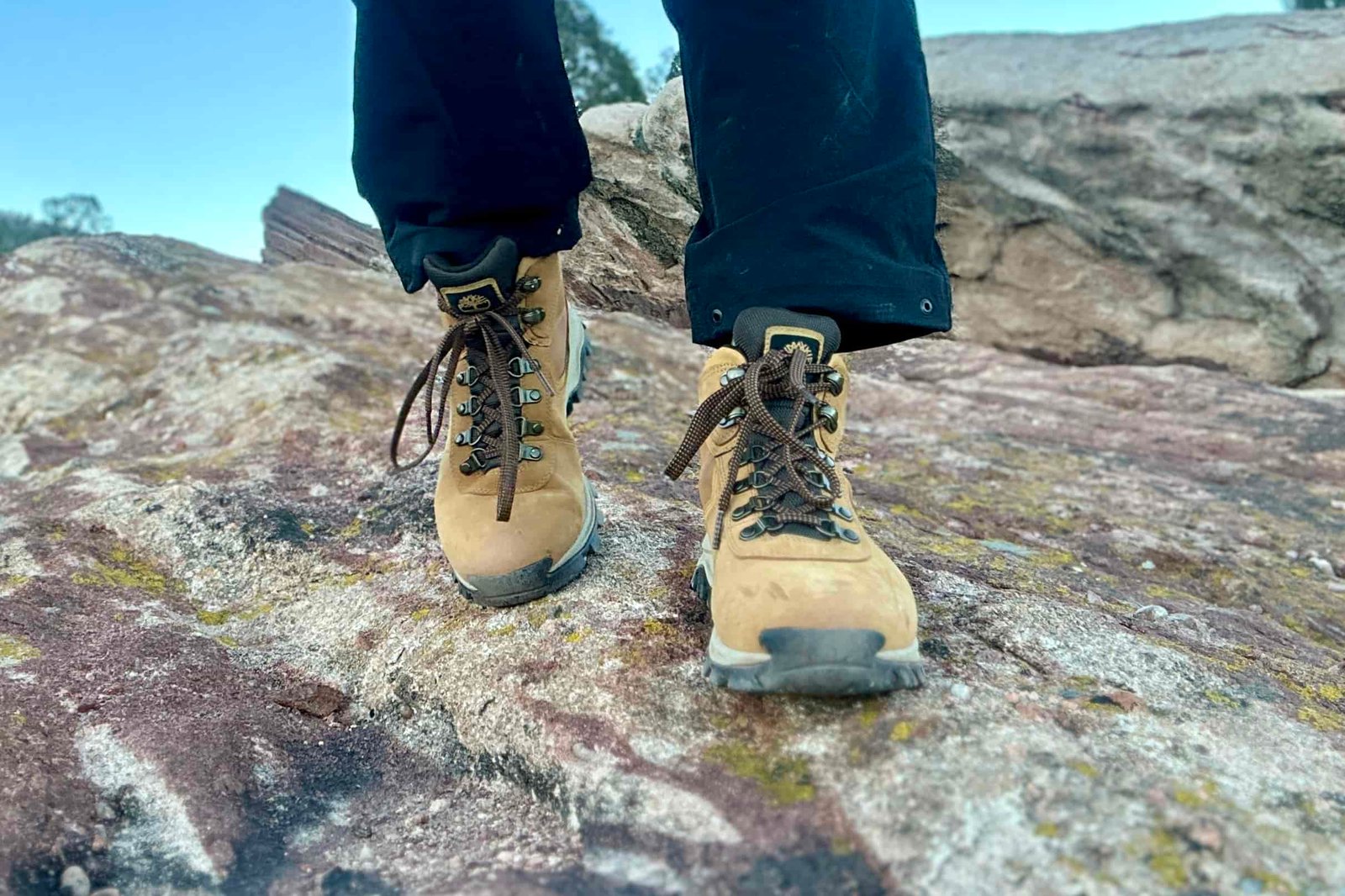 Close up from knees down of a person walking towards the camera wearing hiking boots.