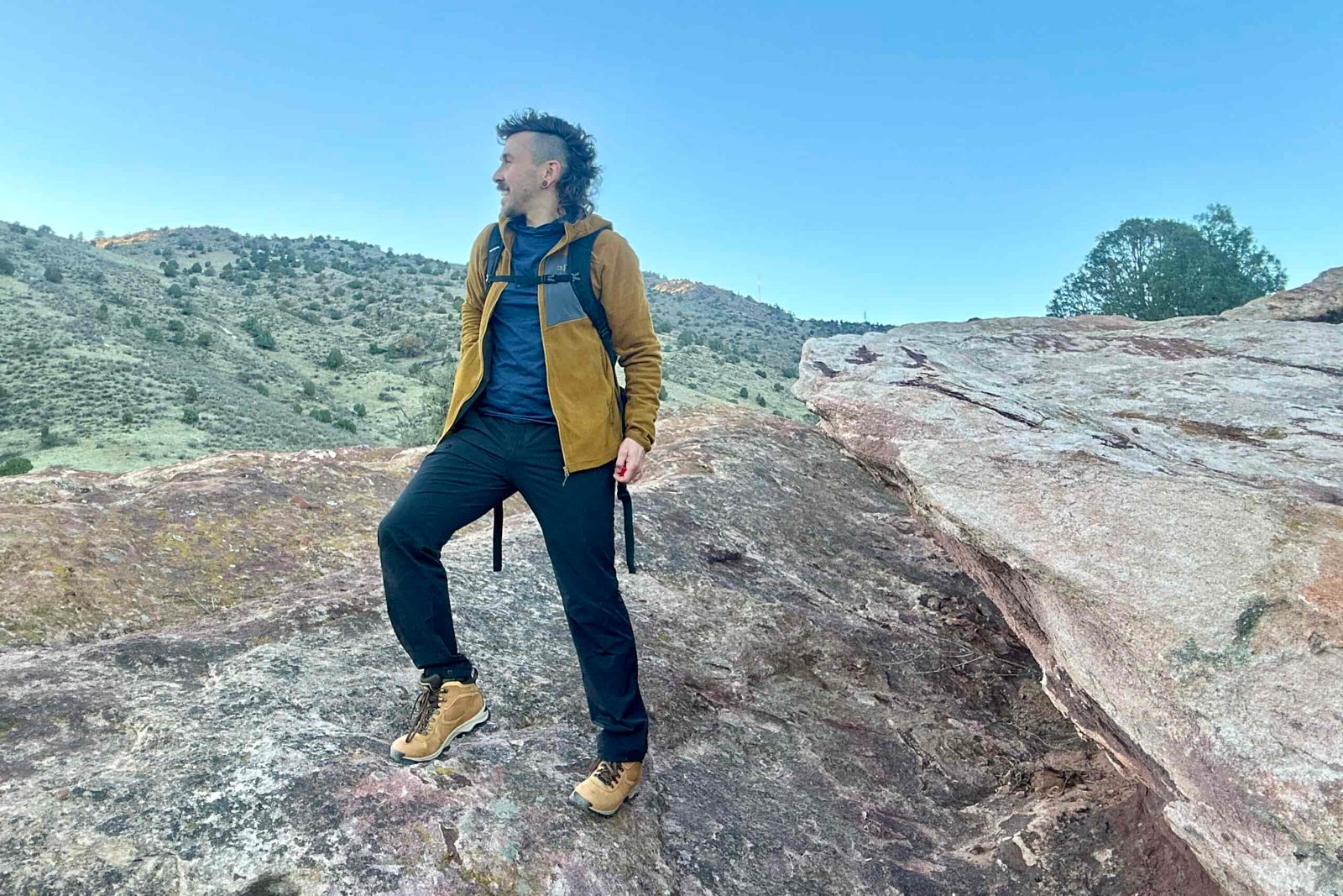 A man hikes in a fleece during sunset in a desert setting.