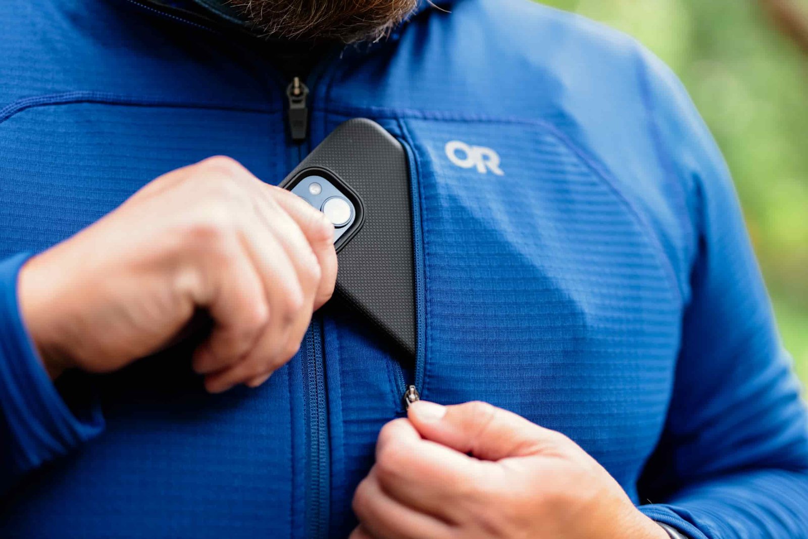 a man puts his cell phone in the chest pocket on the Outdoor Research Vigor Fleece Jacket