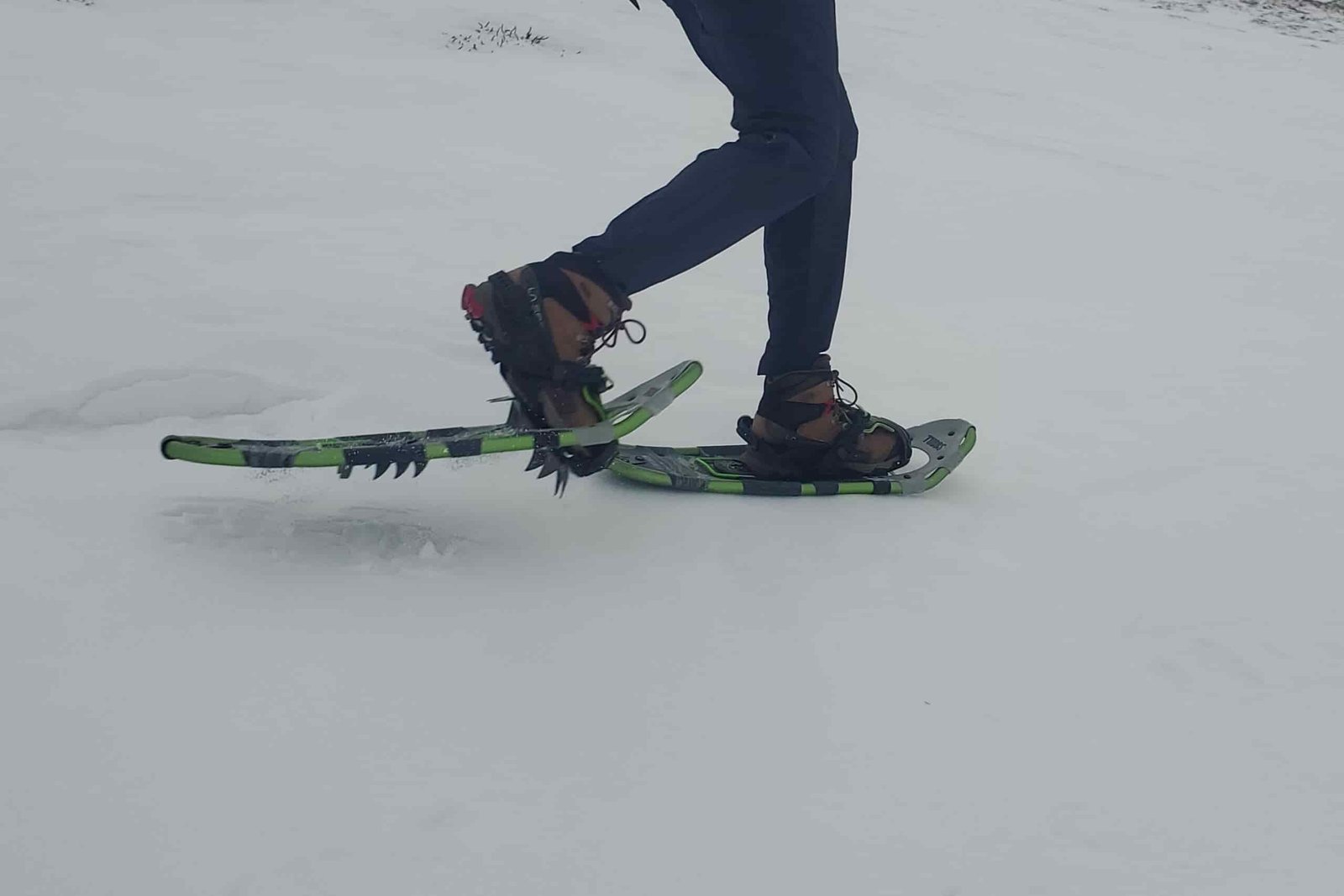 A person walks wearing snowshoes mid stride
