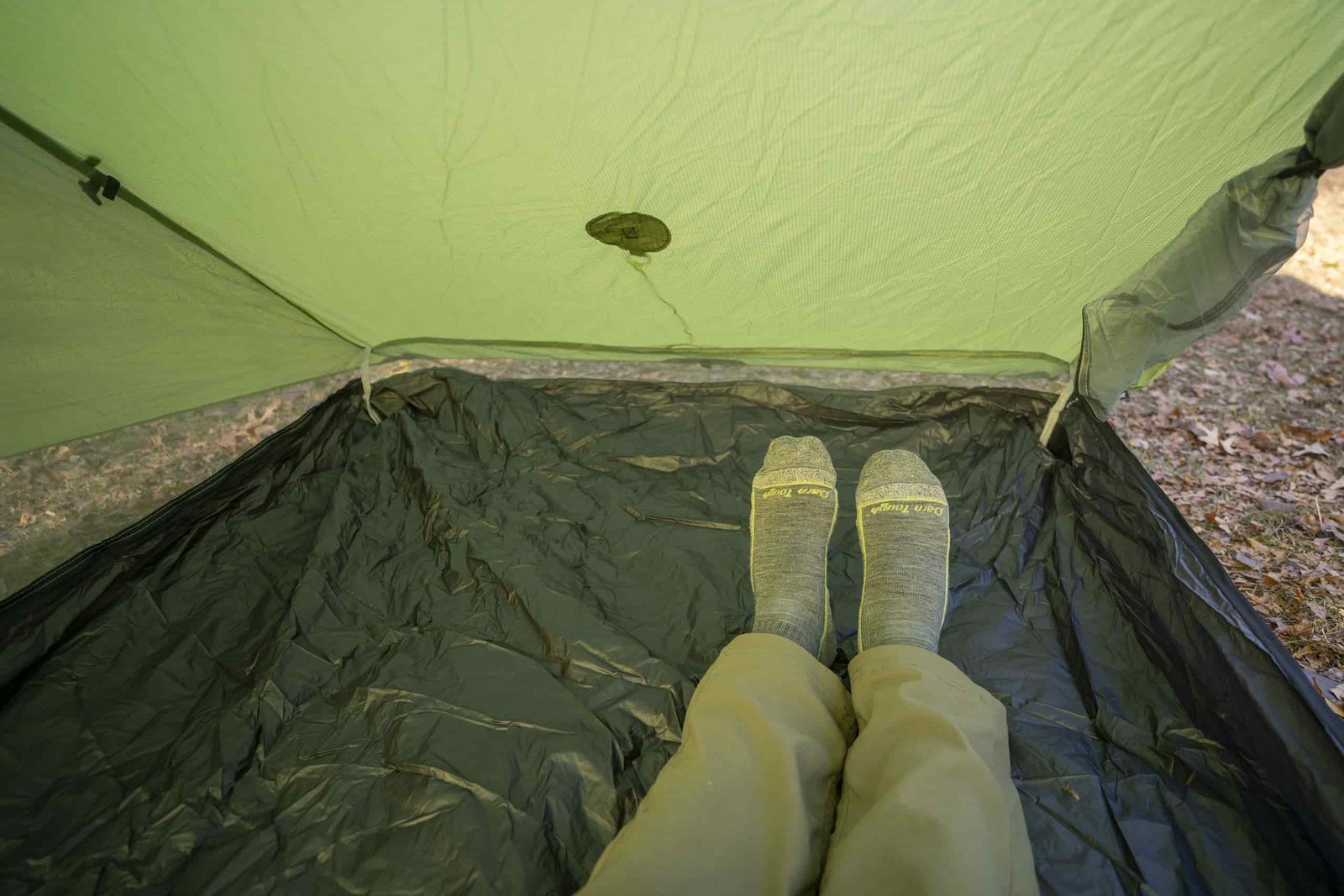 a pair of legs extend into a green tent interior