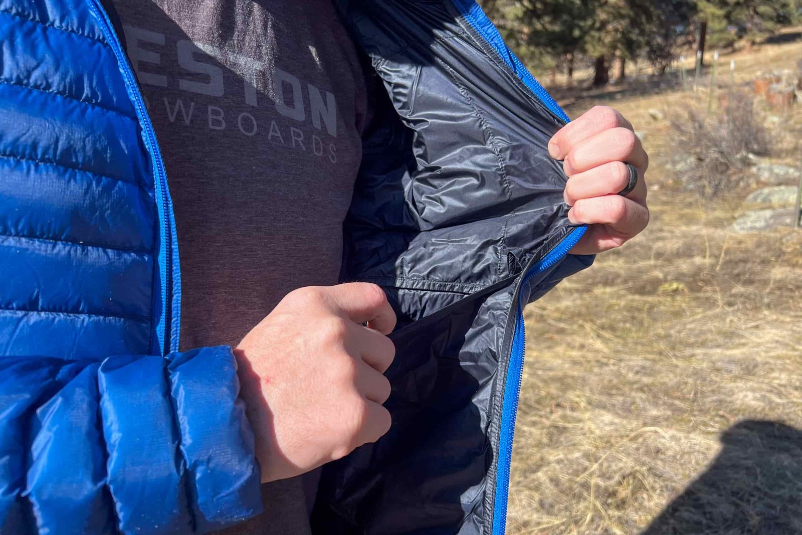 A close-up of someone holding open the inside of the Black Diamond Approach Down Hoody, showing its internal chest pocket.