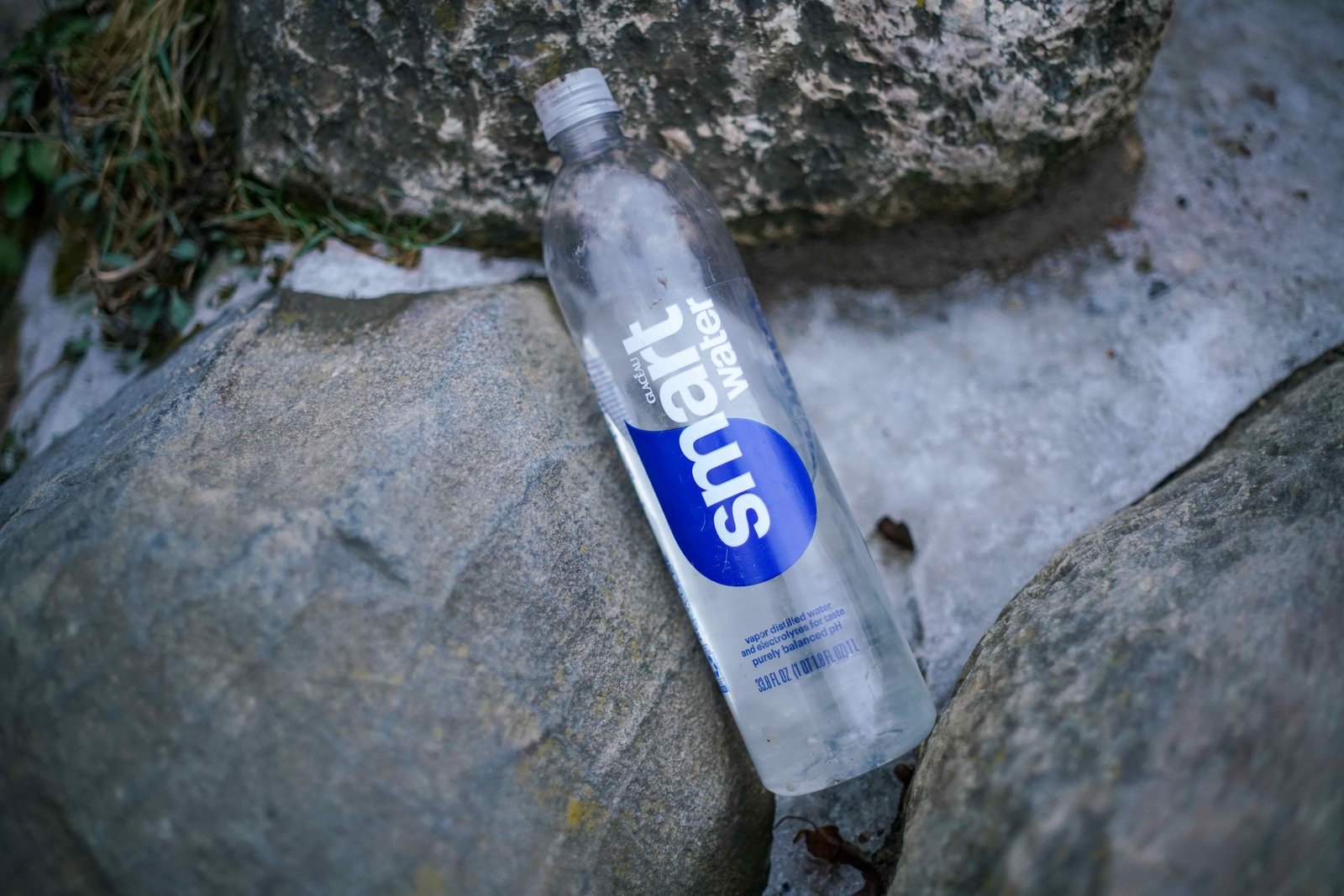 A bottle of Glaceau Smartwater lays on a rock and snow.