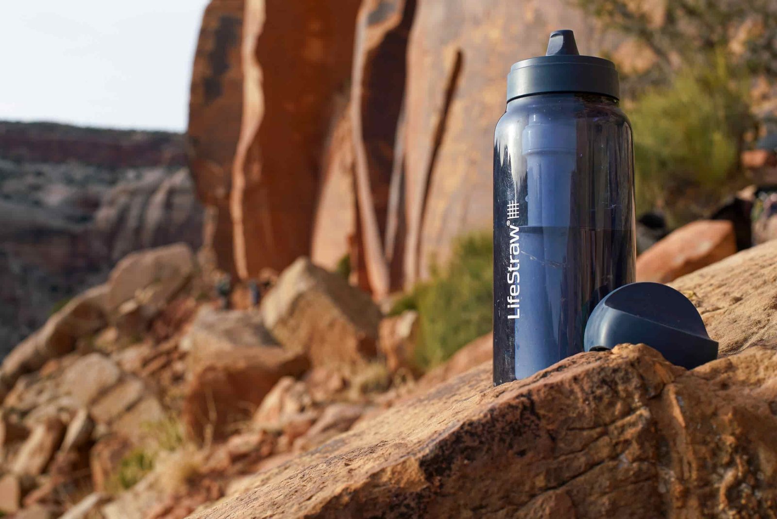 The LifeStraw Go Series water bottle sits on a rock with a mesa in the background.