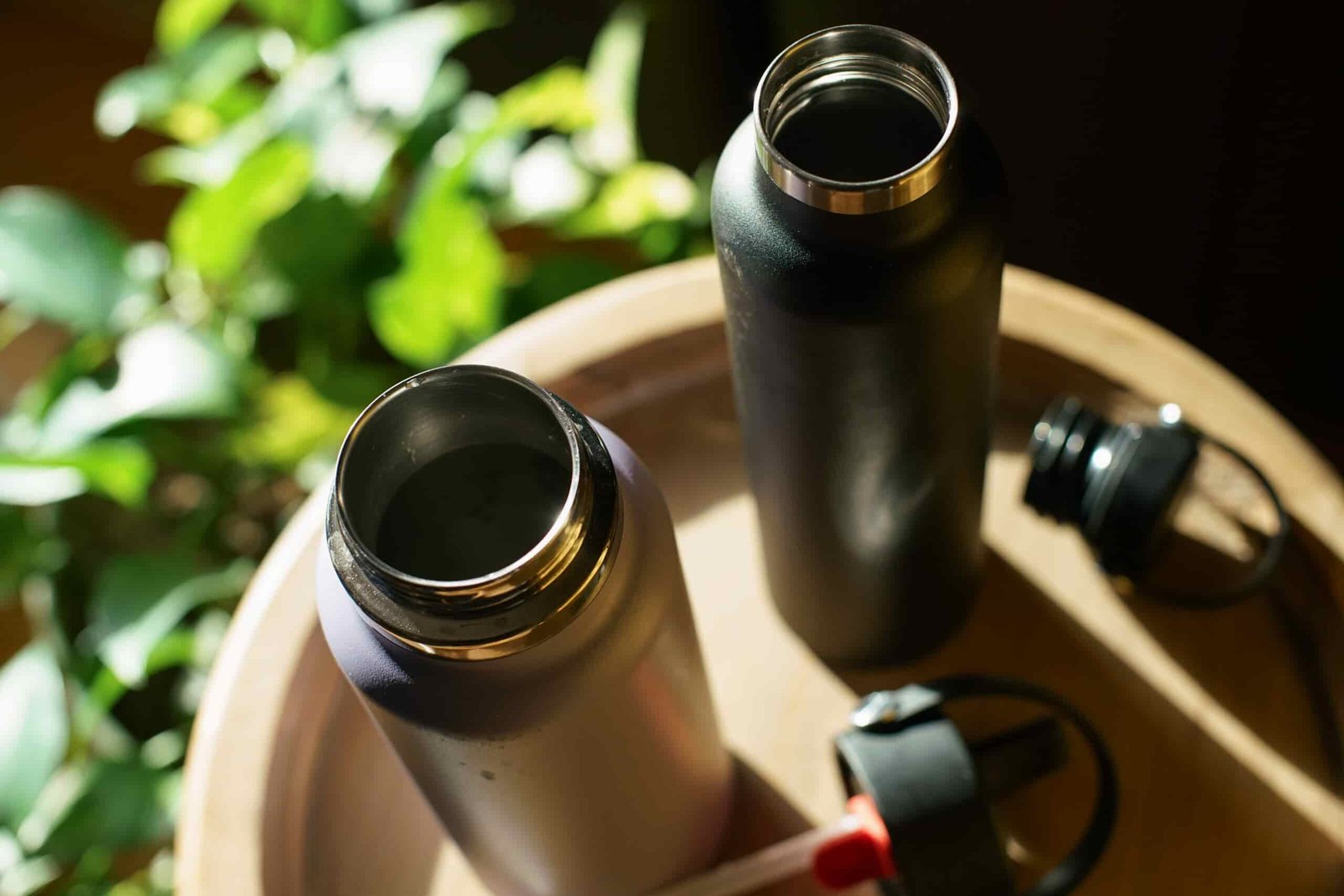 A top down look at the wide and narrow mouths of the The Hydro Flask Wide Mouth and Hydro Flask Standard Mouth. The lids of the bottles sit next to them.