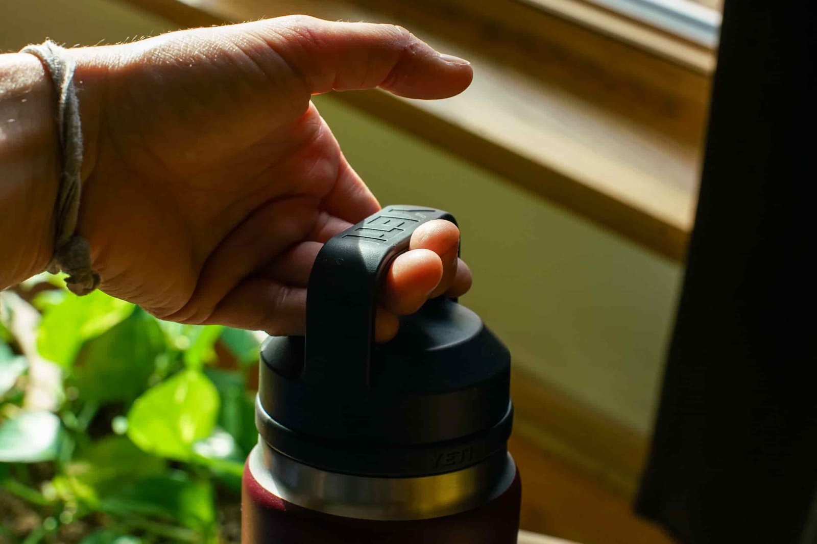 A close up of a hand holding the handle of the YETI Rambler water bottle.
