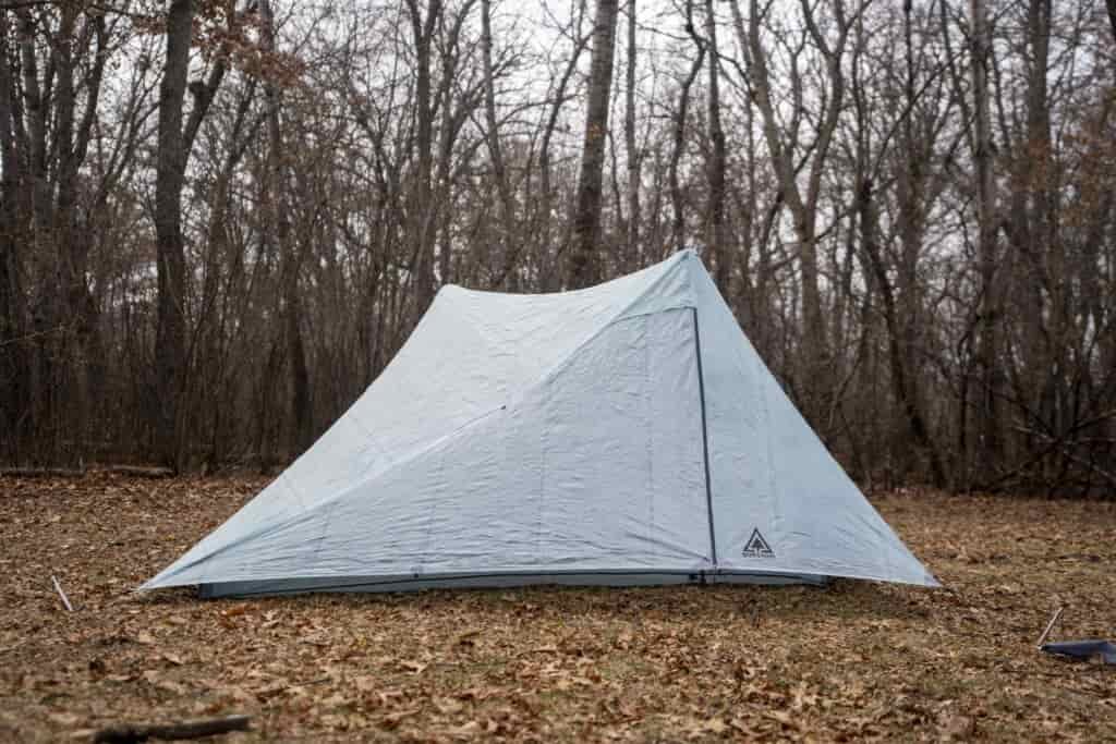 a two person trekking pole tent in a forest clearing
