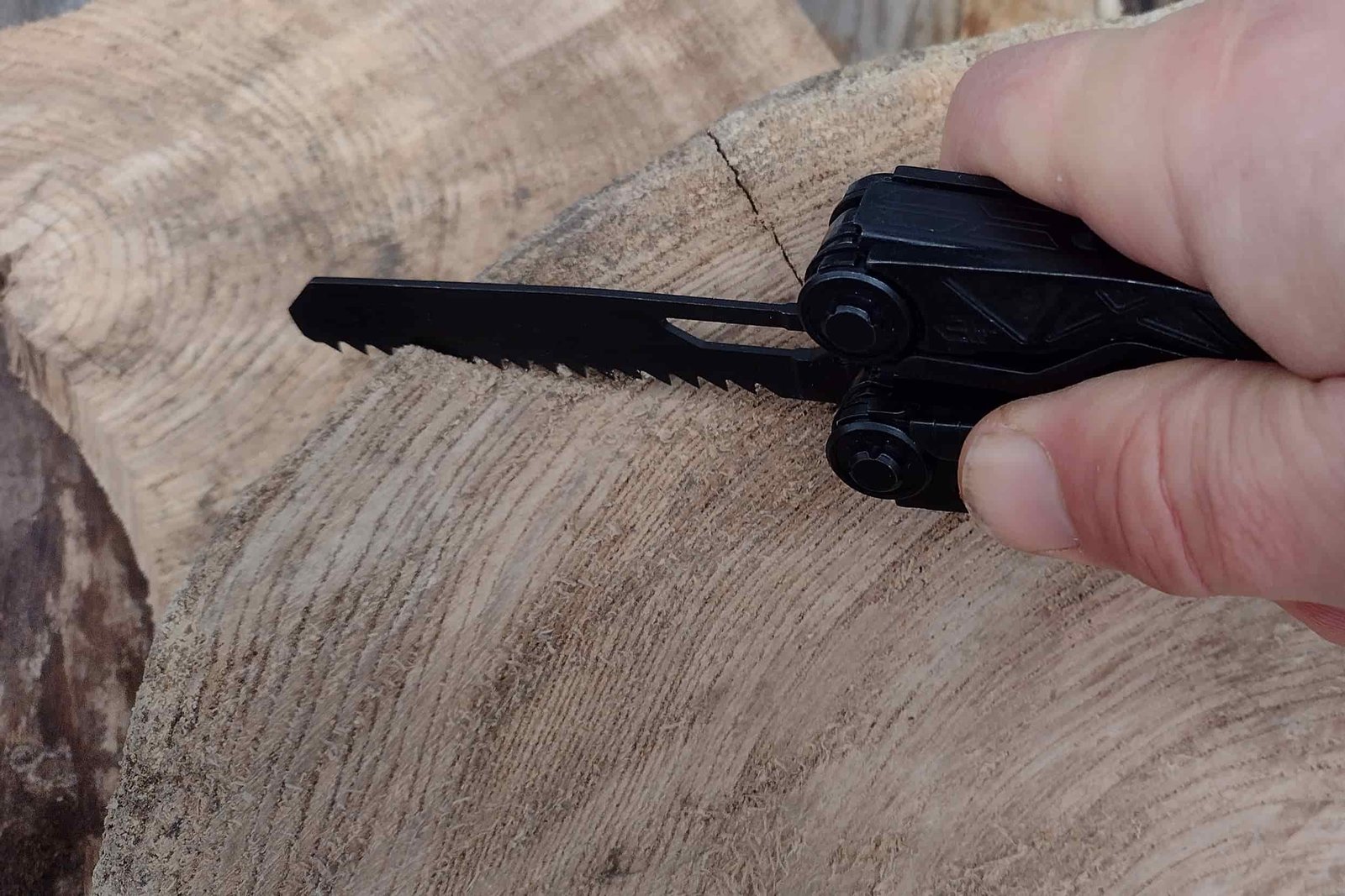The Gerber Dual Force with its saw extended, in hand and cutting into a log slice.