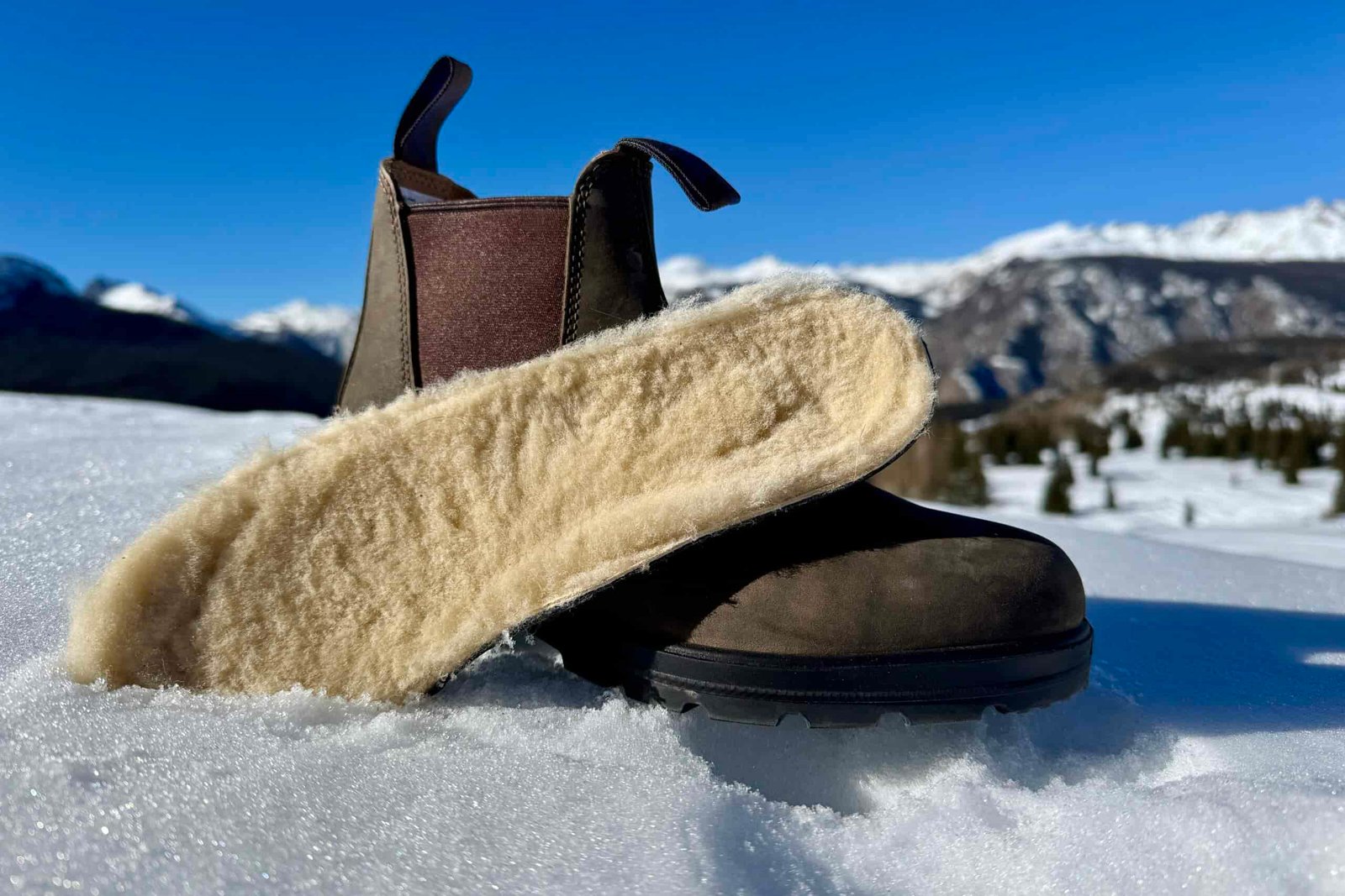 A close up of the Blundstone boot with the insole sitting next to it. They are set on some snow in the mountains.