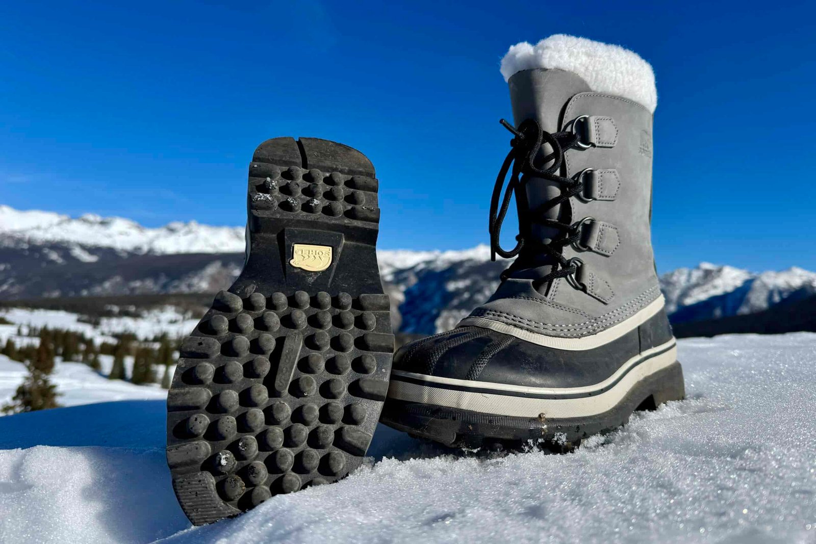 A close up of the tread on the bottom of the Sorel boot. It is sitting in the snow in the mountains.