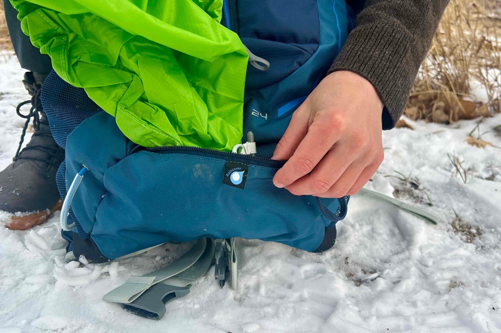 Close up of a person pulling out the rainfly from the bottom of their daypack.