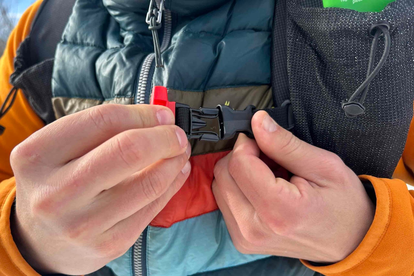 Close up image of a person buckling a buckle on their backpack.