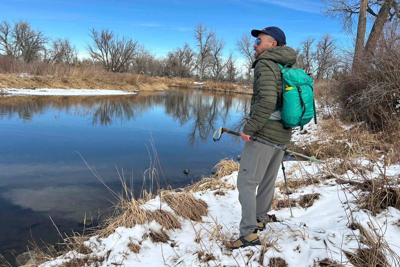A man hiking next to a river in a snowy wilderness area.