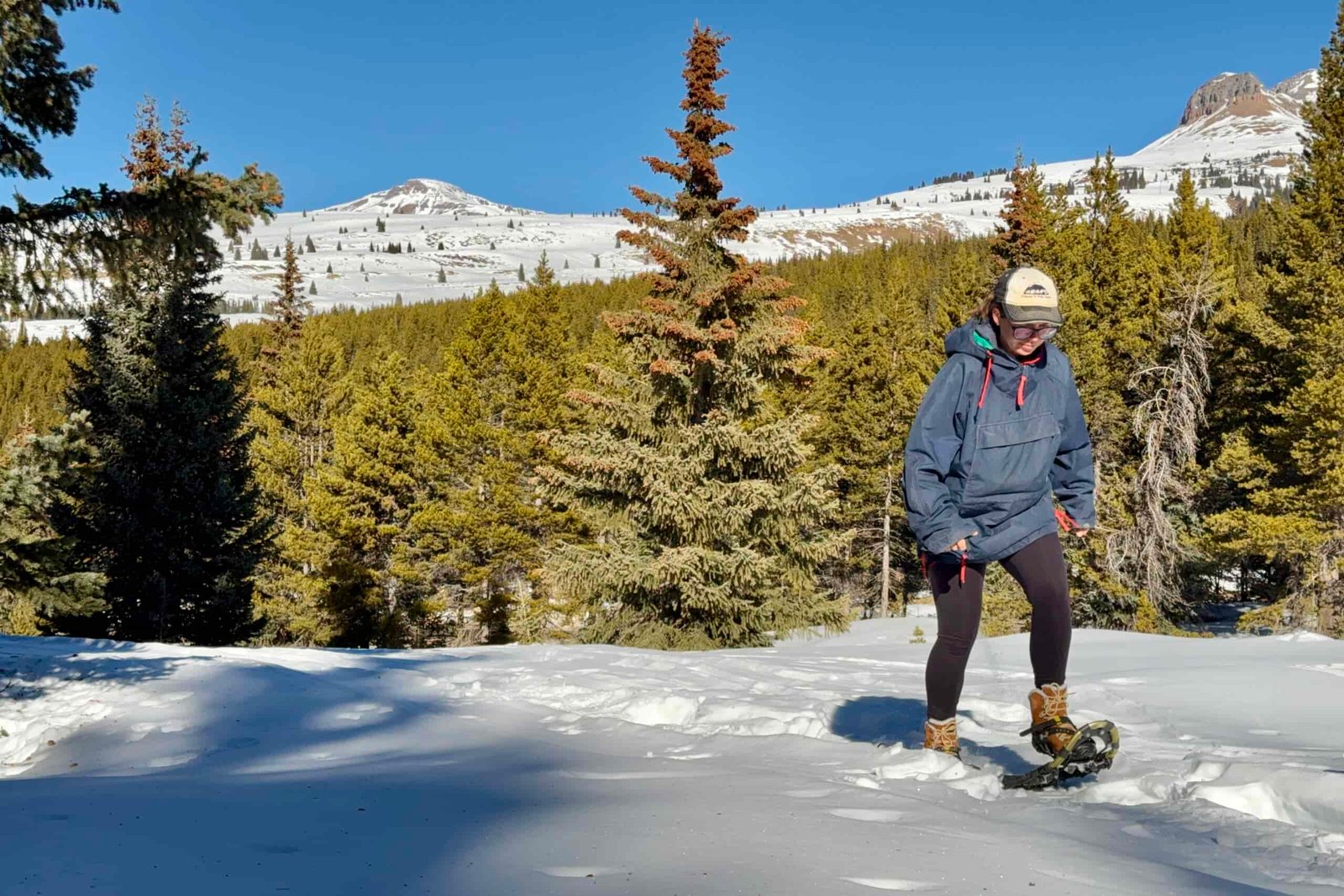 A person wearing the Bridger boots is snowshoeing in the mountains.
