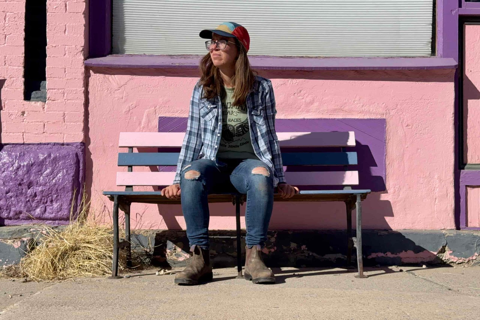 A person wearing the Blundstone Thermal Chelsea boots is sitting on a brightly colored bench in front of a brightly colored building.