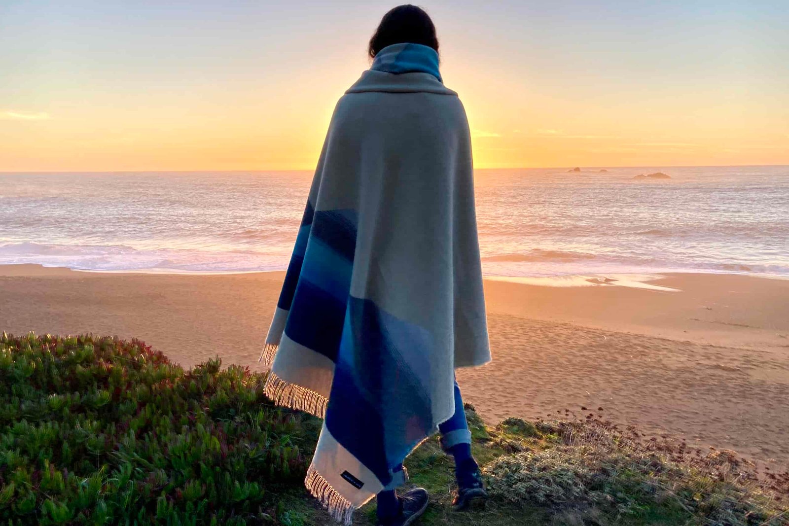 Women standing on the beach watching the sunset while wrapped in the Sackcloth and Ashes blanket.