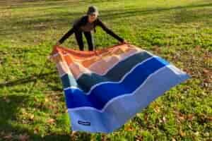 Women laying out the Nomadix Festival Blanket on a patch of grass