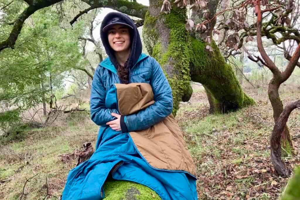 Women sitting on log with the REI camp blanket used as a throw over her legs