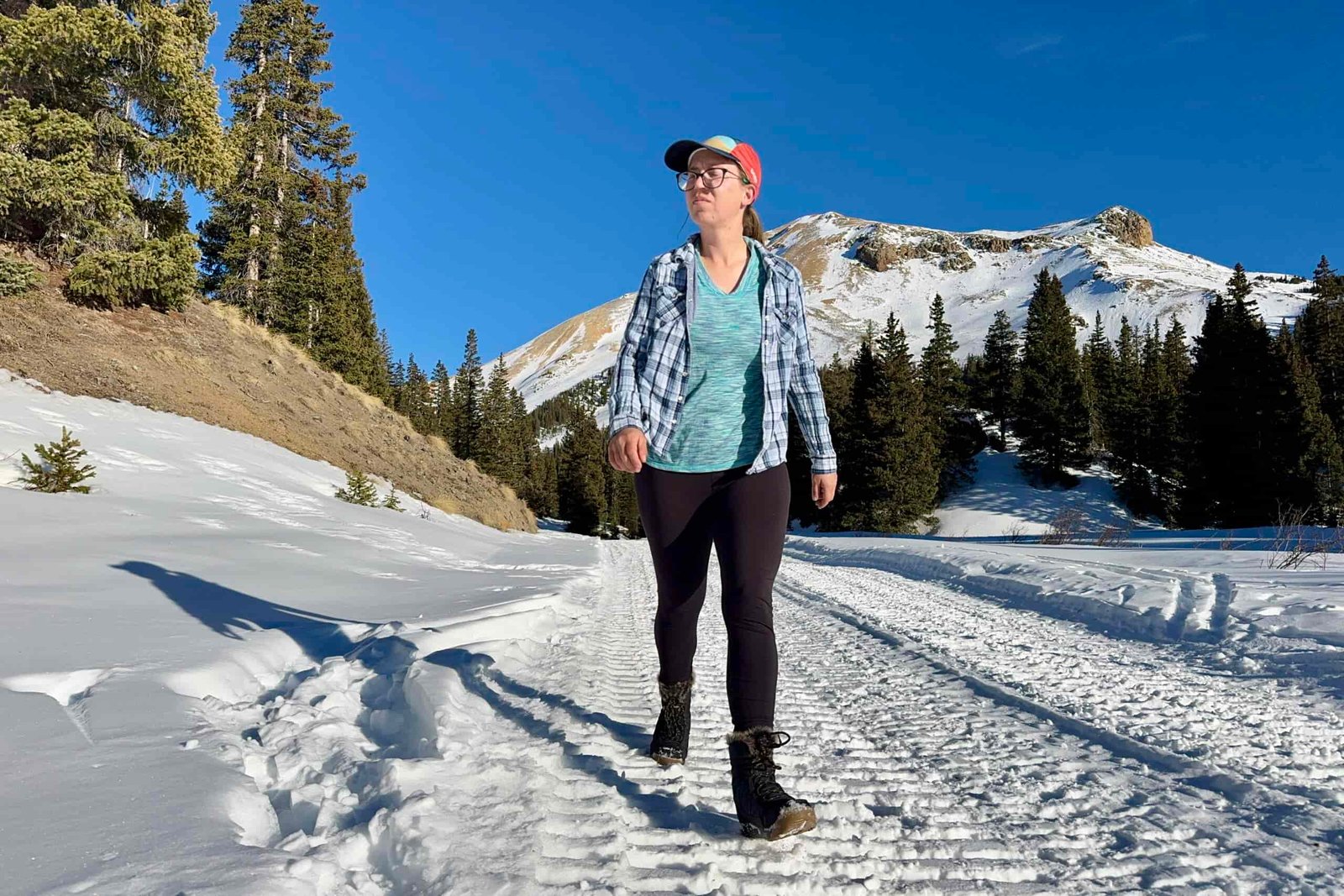 A person walking in the snow while wearing the Minx Shorty boots in the mountains.