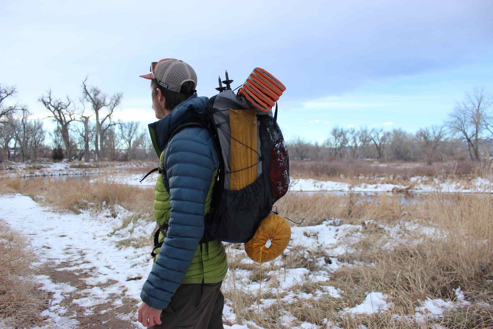 A profile view of a hiker wearing the Zpacks Arc haul ultra with tent poles, a sleeping pad, and tent packed on the outside.