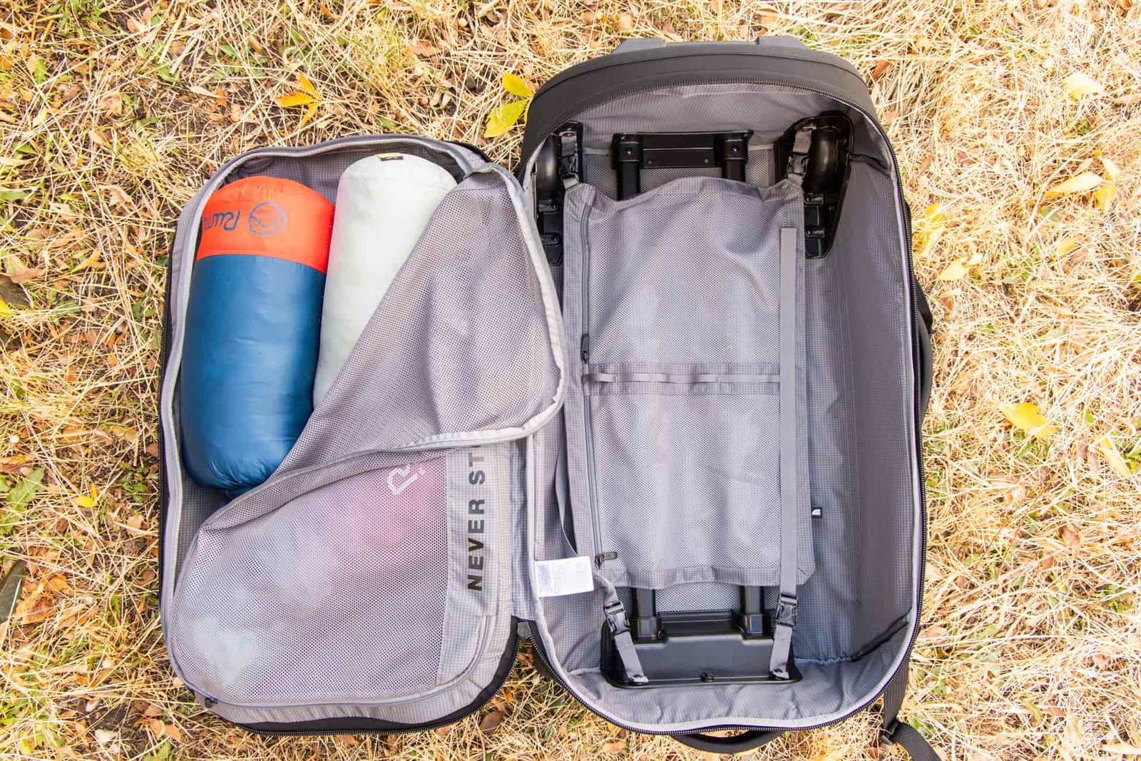 An open bag with an empty main compartment but several blankets visible from a half-opened compartment on the inside of the lid.